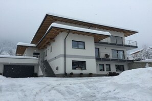 Ein modernes, zweigeschossiges Haus mit Flachdach, Garage und Balkon.