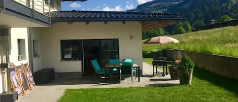 Un bâtiment moderne doté d’un patio aménagé avec des espaces de détente en plein air et un barbecue.