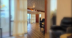 Ein Hotelzimmer mit Holzboden, einer schwarzen Ledersofa, einem kleinen Tisch und Blick durch eine Glastür.