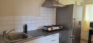 Ett kompakt kök med en gasspis, en diskho i rostfritt stål och ett kylskåp.