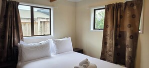A hotel room with a bed, two windows, and curtains. - Calm and Private Lower Level Home in Mount Roskill (Auckland)