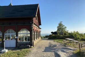 A building with a red facade and a gravel path leading to outdoor seating. - Gebirgshäusl Oybin / Zittau Mountains (Oybin)