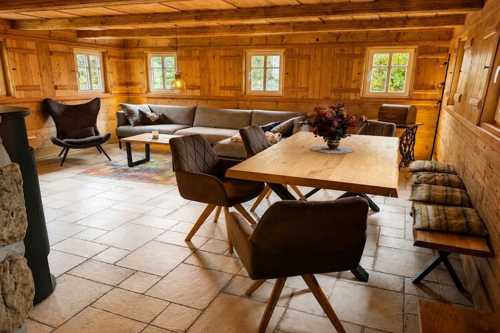 A cozy cabin interior with a wooden dining table, cushioned seating, and a fireplace.