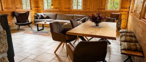 A cozy cabin interior with a wooden dining table, cushioned seating, and a fireplace.