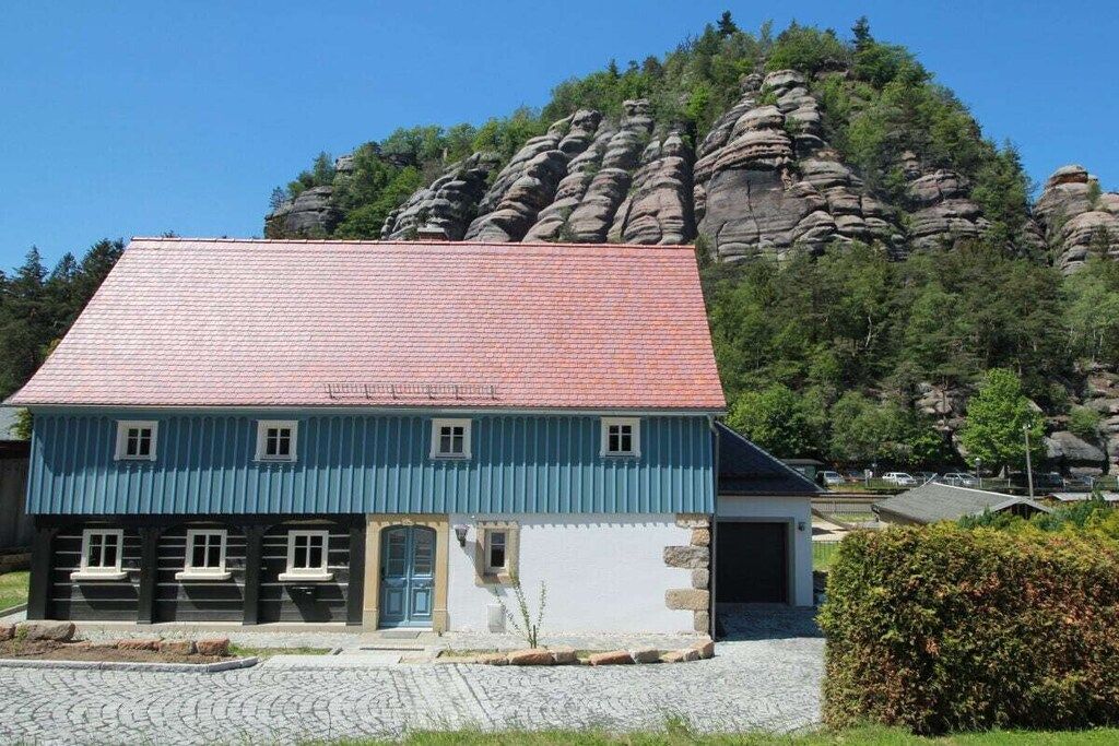 A two-story building with a red-tiled roof, a blue facade, and a stone foundation.