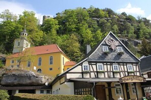 A traditional building with a sign that reads 'Burgfeller' in front of a forested hill. - Gebirgshäusl Oybin / Zittau Mountains (Oybin)