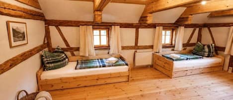 Une pièce avec deux lits en bois, une fenêtre et un tableau encadré au mur.