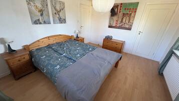 Une chambre à coucher avec un lit en bois, une table de chevet, une commode et un mur décoré d’œuvres d’art.