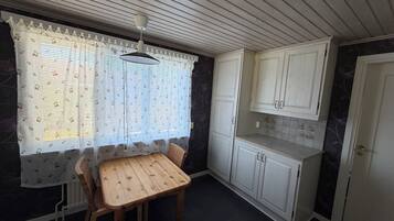 Une cuisine avec une table à manger, des chaises et des armoires blanches.