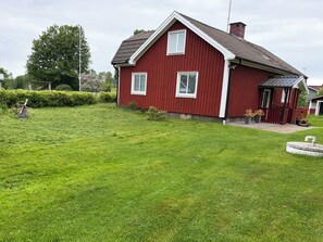 A red house with a sloped roof and a well-maintained lawn.