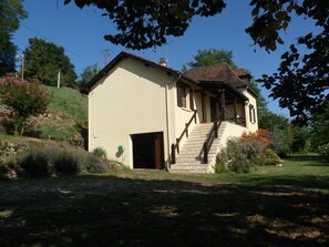 Ein kleines, eingeschossiges Gebäude mit Satteldach, einer Holztreppe, die zu einer Veranda führt, und einer Tür.