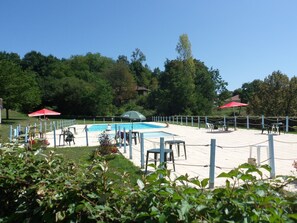Ein Poolbereich mit Zaun, Stühlen und Sonnenschirmen.