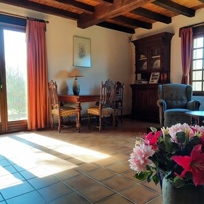 Una habitación con techo de madera, una mesa de comedor con sillas, un armario y una ventana con cortinas.