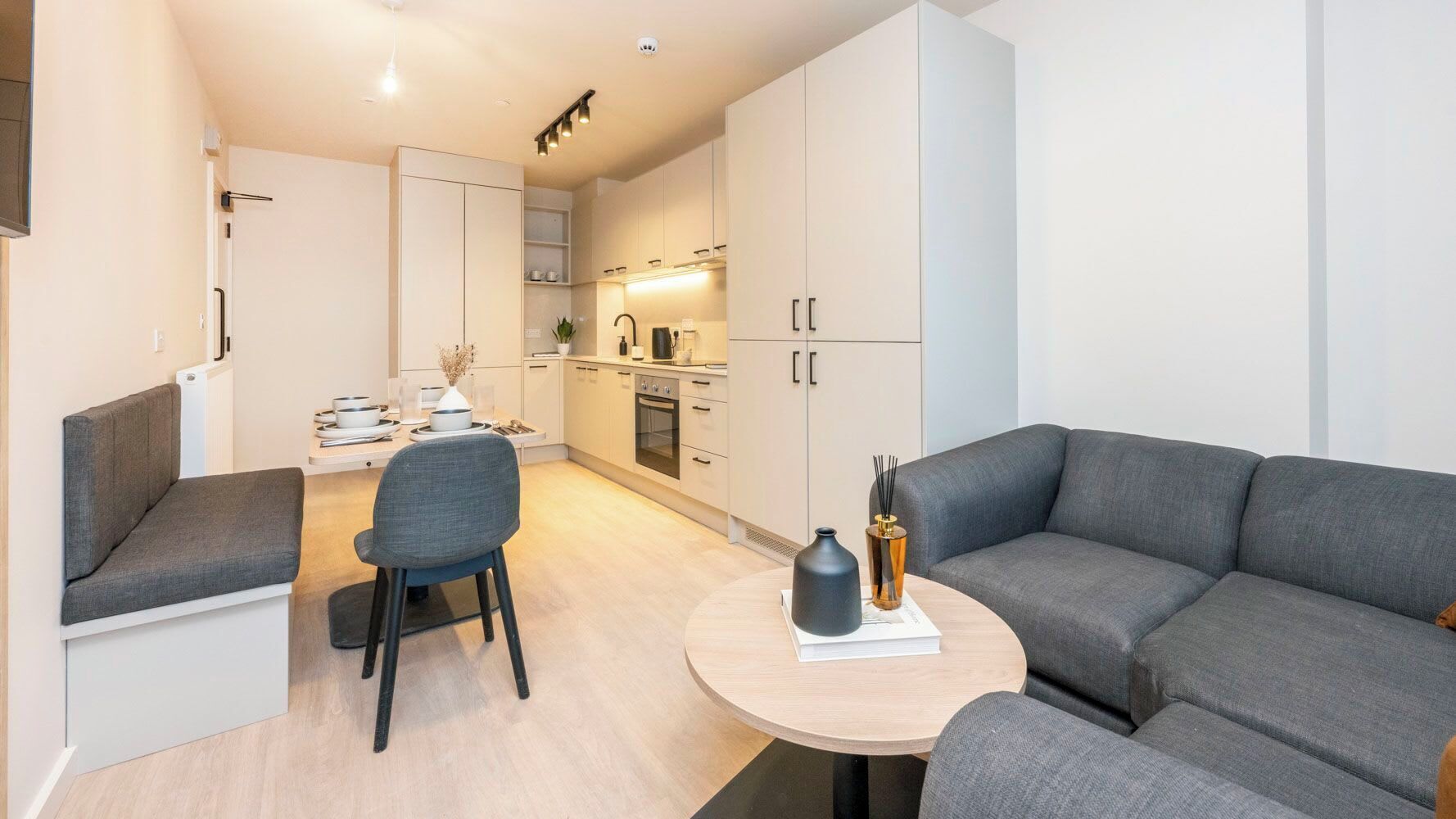 A modern living space with a sofa, a dining table, and a kitchen area.
