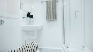 Une salle de bain moderne avec une douche à parois de verre, un lavabo blanc et une serviette à motifs noirs et blancs.
