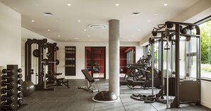 A gym with various exercise equipment, a weight rack, and a large pillar.