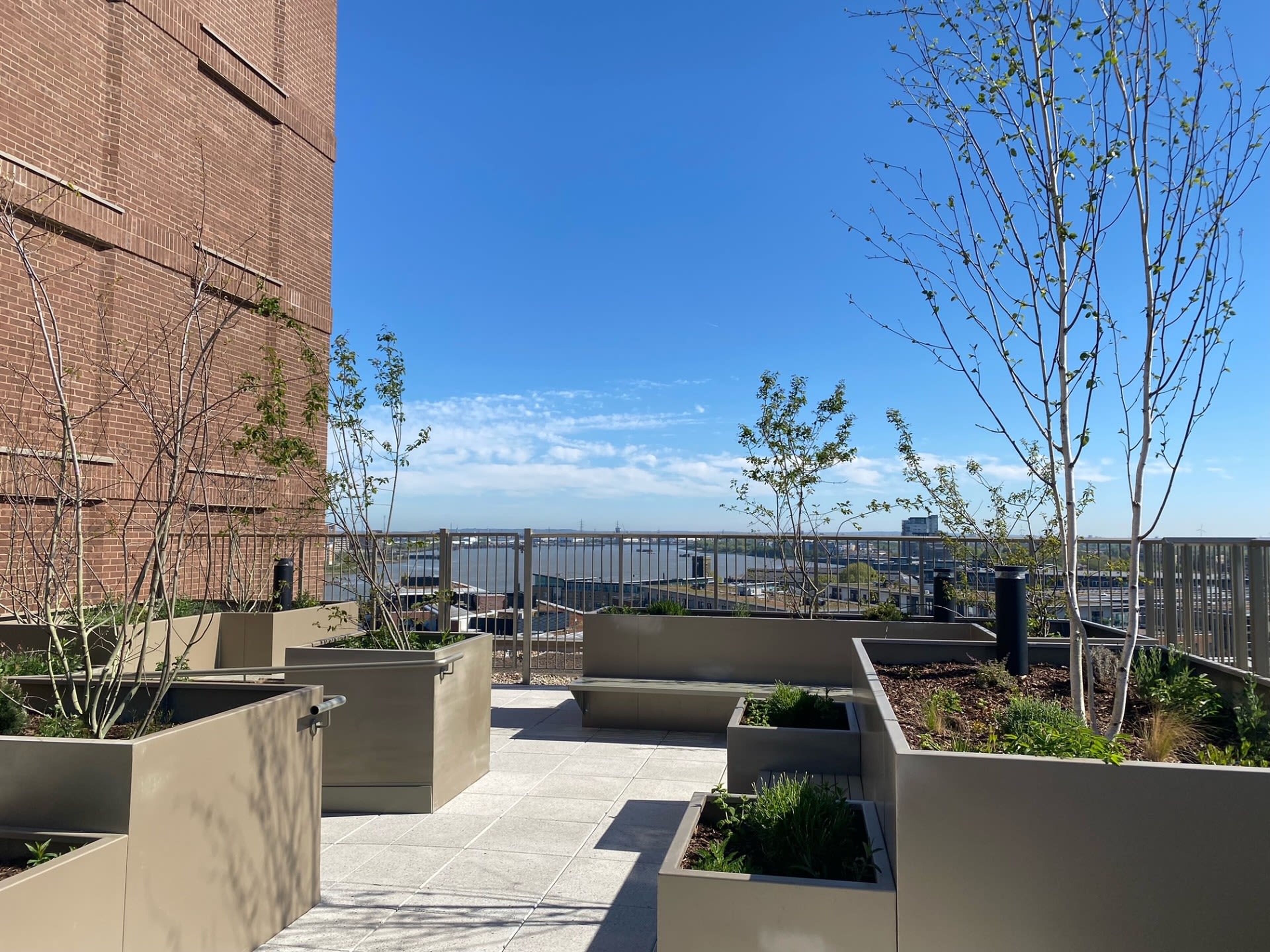 A rooftop terrace with planters and a view of a bridge.