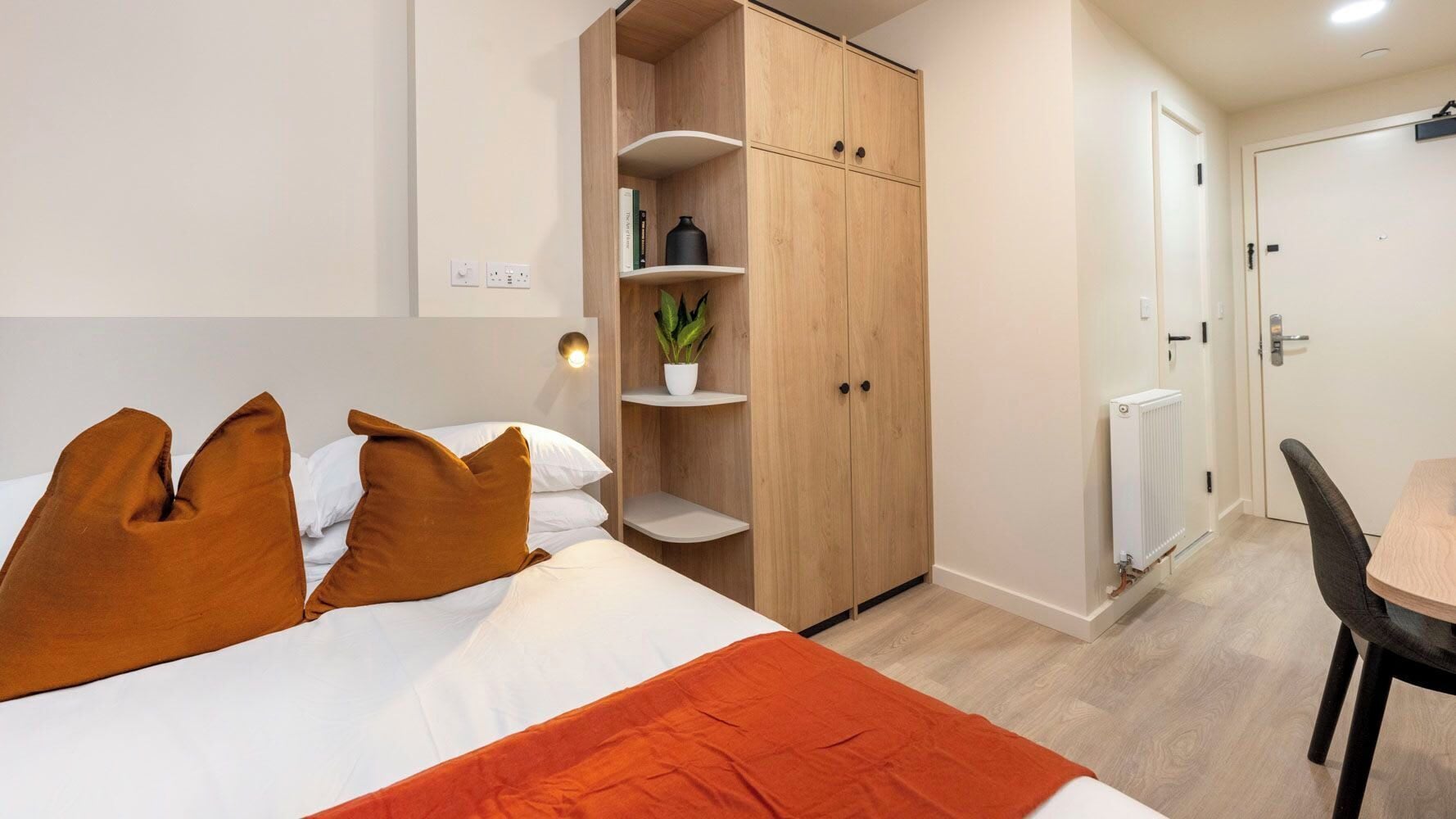 Une chambre d’hôtel avec un lit, une armoire, un bureau et une chaise.