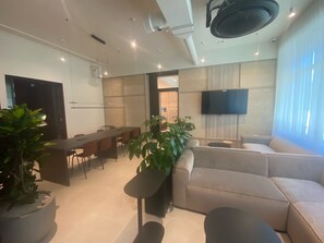 A modern living room with a sofa, a dining table, chairs, and a TV. - Student Only Press House (London)