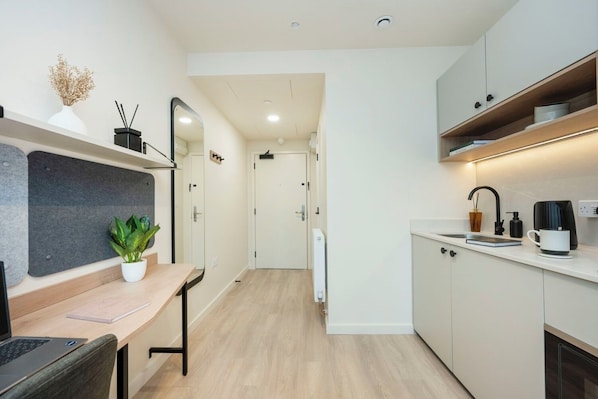 A modern kitchen with a dining area, a small plant, and a coffee machine.