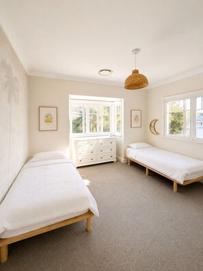 A bedroom with two single beds, a dresser, and a large window with a view of greenery. - Beautiful Hamptons style home, just a short walk from the Beach, shops & cafés. (Freshwater)