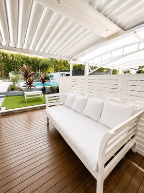 A white outdoor seating area with a wooden deck, a white bench, and a white sofa. - Beautiful Hamptons style home, just a short walk from the Beach, shops & cafés. (Freshwater)