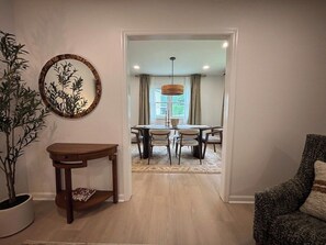 A room with a dining area, a potted plant, and a chair. - Covenanter Classic | Luxe East Side Retreat (Bloomington)