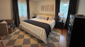 Quarto de hotel com cama, escrivaninha, cadeira, cômoda e luminária.