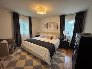 Una habitación de hotel con una cama, un escritorio, una silla, un aparador y una lámpara.