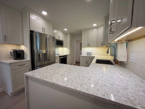 A kitchen with white cabinets, stainless steel appliances, and a granite countertop. - Covenanter Classic | Luxe East Side Retreat (Bloomington)