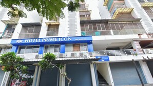 Un hotel llamado 'HOTEL PRIME ICON' con un letrero, unidades de aire acondicionado y persianas cerradas.