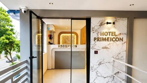 Zona de recepción de un hotel con pared de mármol y mostrador.