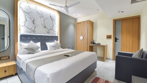 Un dormitorio moderno con una cama grande, una mesita de noche, un armario y una zona de estar.