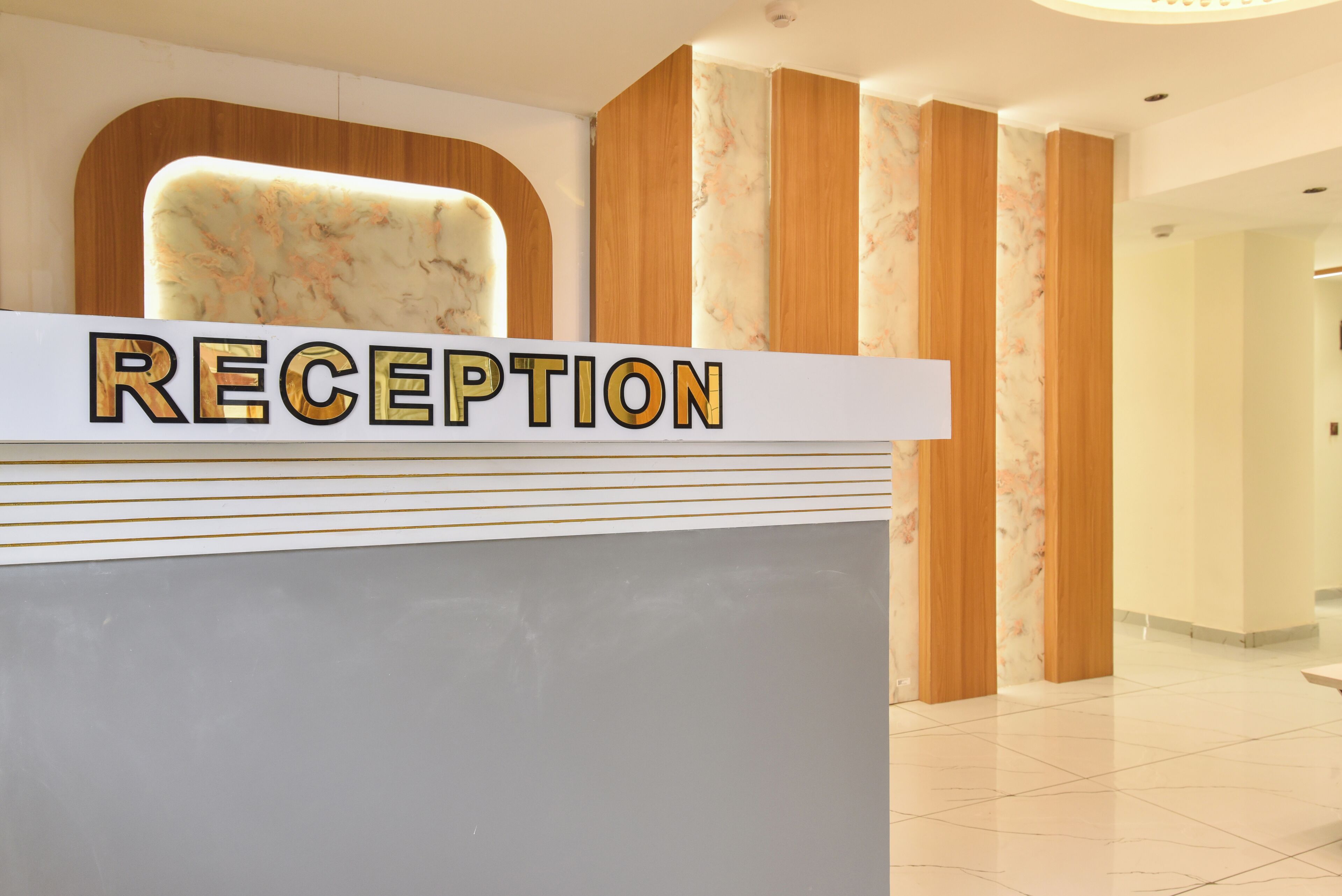 Un mostrador de recepción con un panel posterior de apariencia marmórea y un letrero que dice 'RECEPTION'.