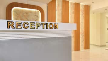 Un mostrador de recepción con un panel posterior de apariencia marmórea y un letrero que dice 'RECEPTION'.