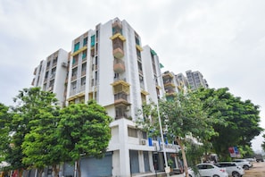Un edificio residencial de varios pisos con balcones, unidades de aire acondicionado y una combinación de persianas abiertas y cerradas.