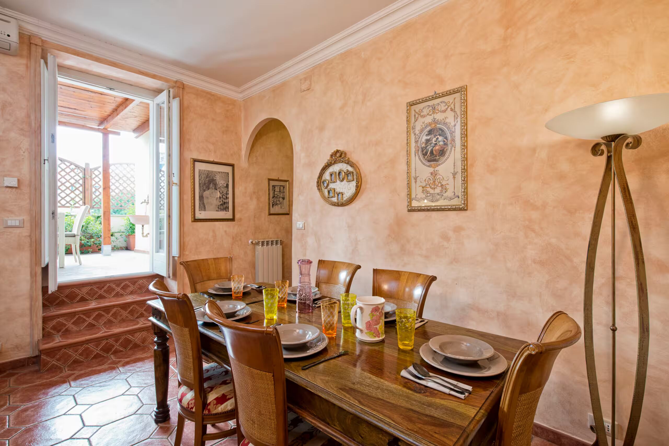A dining area with a wooden table set for four, surrounded by chairs.