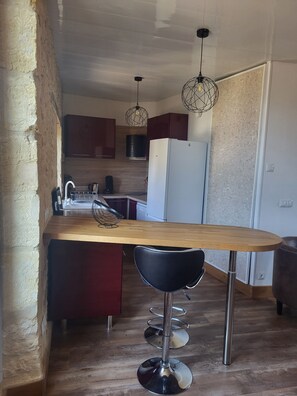 A kitchen with a wooden island, stainless steel bar stools, and pendant lighting. - A typical Dordogne apartment (Sarlat-la-Canéda)