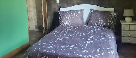 Un dormitorio con una cama, una lámpara colgante, un espejo en la pared y una mesita de noche con lámpara.