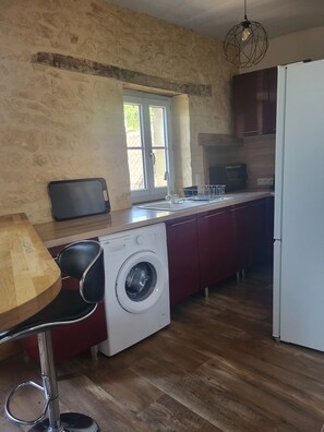 A compact kitchen with a washing machine, a sink, and a microwave. - A typical Dordogne apartment (Sarlat-la-Canéda)