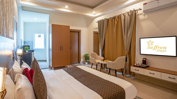 Una habitación de hotel con cama, escritorio, silla, televisor y ventana con cortinas.