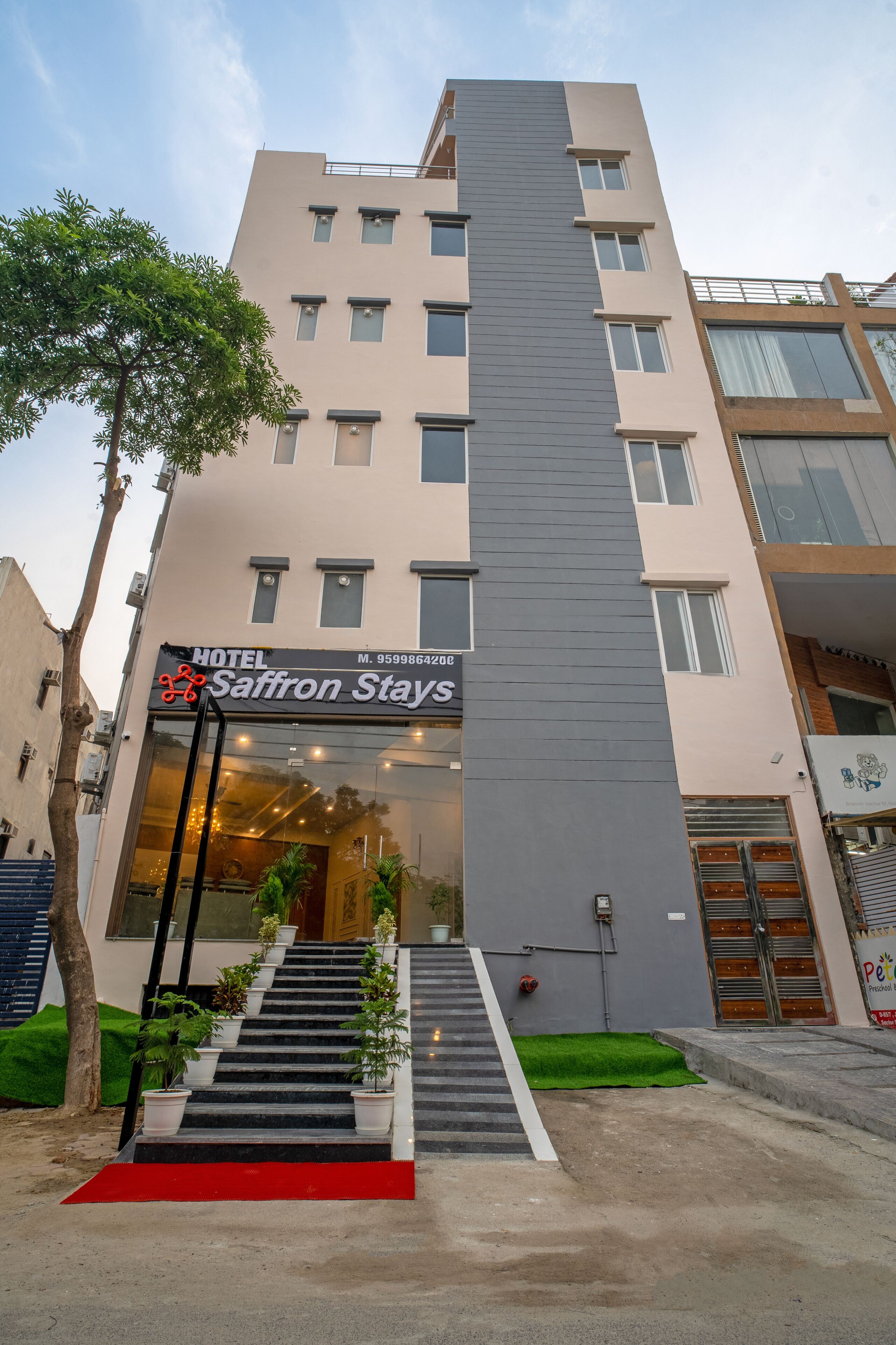 A hotel with a modern facade, a staircase leading to the entrance, and a red carpet.