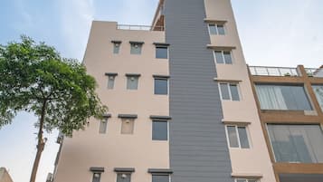A hotel with a modern facade, a staircase leading to the entrance, and a red carpet.