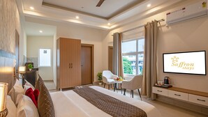 Habitación de hotel con cama, escritorio, silla, televisión y ventana con cortinas.