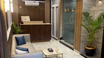 A modern lobby with a reception desk, seating area, and a chandelier.