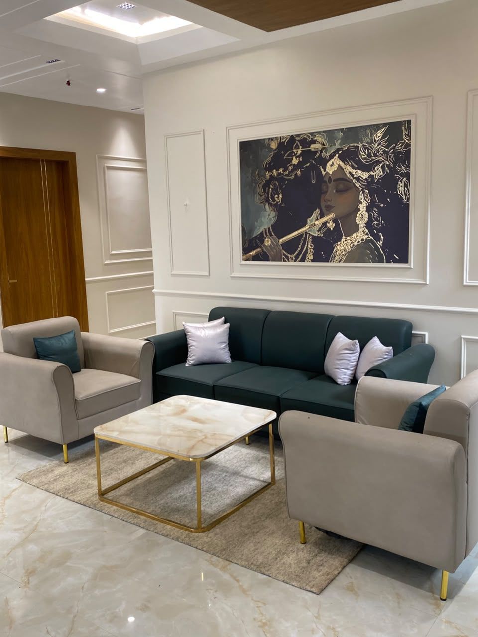 Una sala de estar moderna con un sofá, sillones, una mesa de centro y un cuadro abstracto grande en la pared.