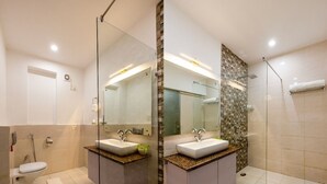 Et moderne badeværelse med en glas brusekabine, en hvid vask og et toilet.