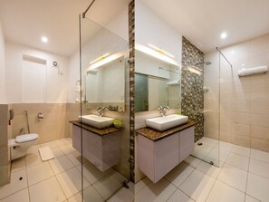 Un baño moderno con cabina de ducha de vidrio, lavabo blanco y un inodoro.