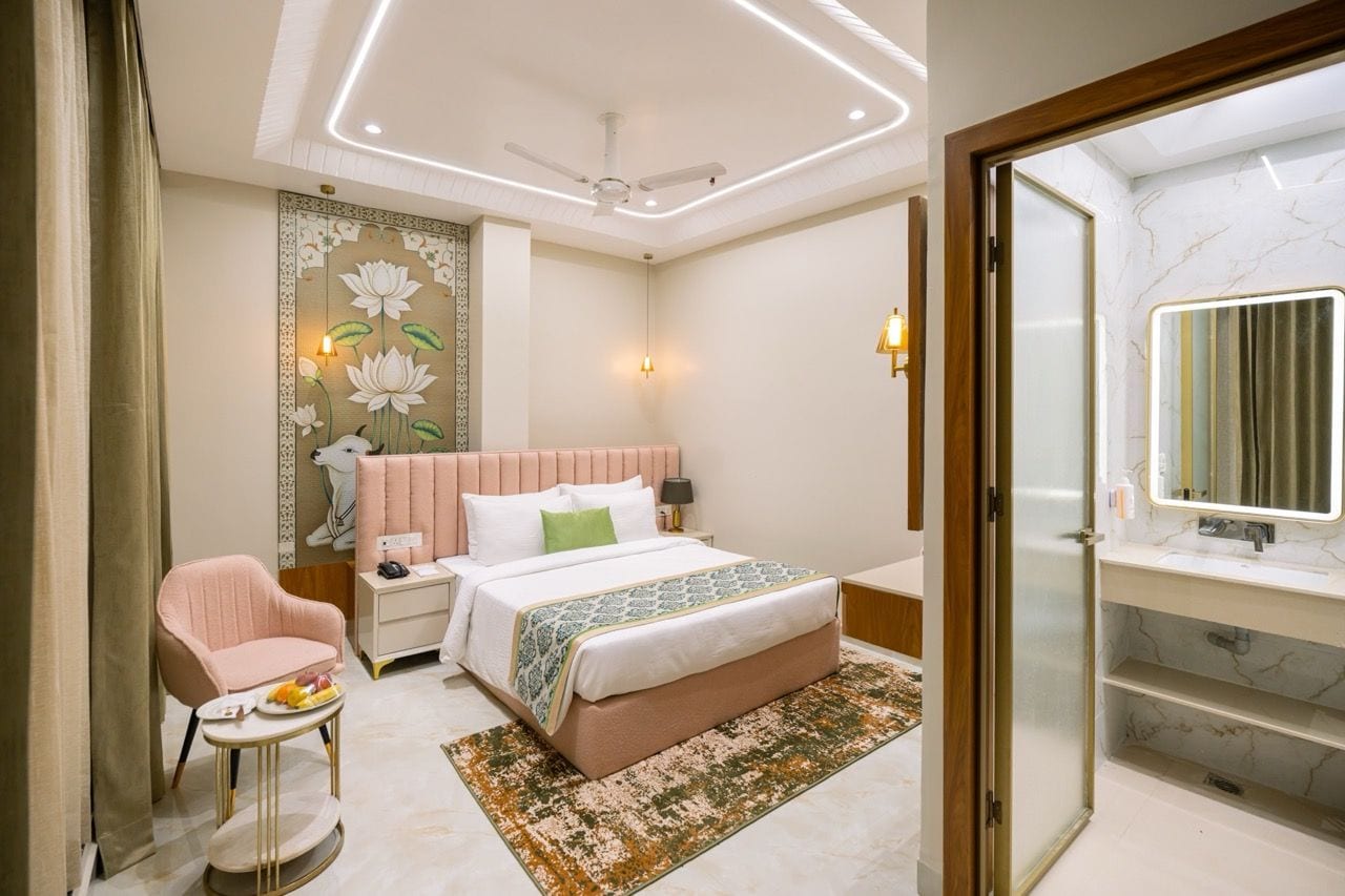 A modern bedroom with a bed, bedside table, chair, and a bathroom with a mirror and sink.