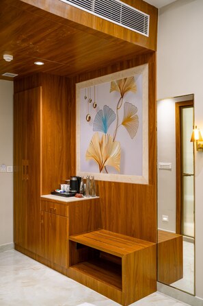 A hotel room with a wooden panel wall, a built-in bench, a coffee machine, and a decorative wall piece.